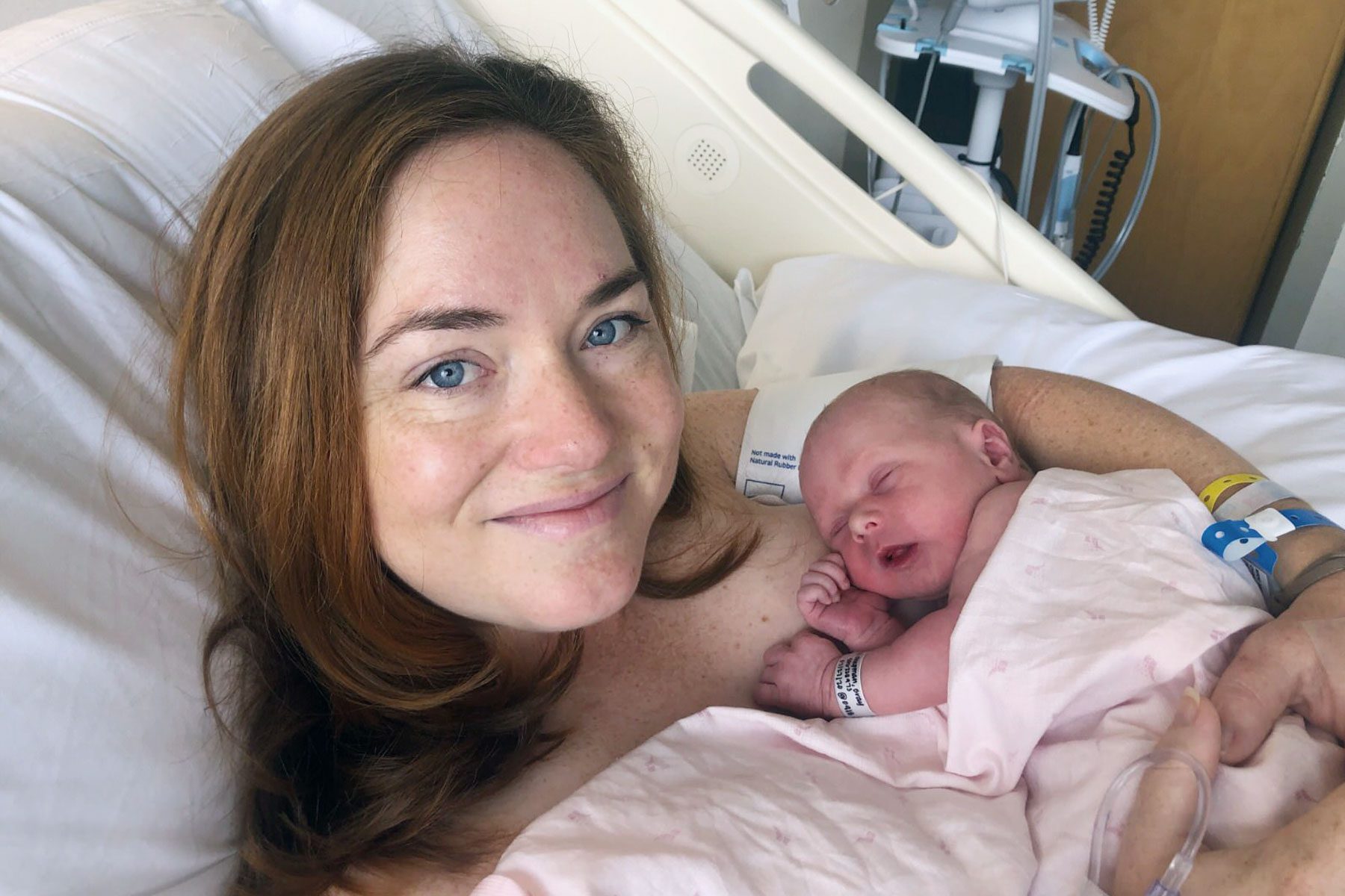 A mother holds her newborn in a hospital bed.