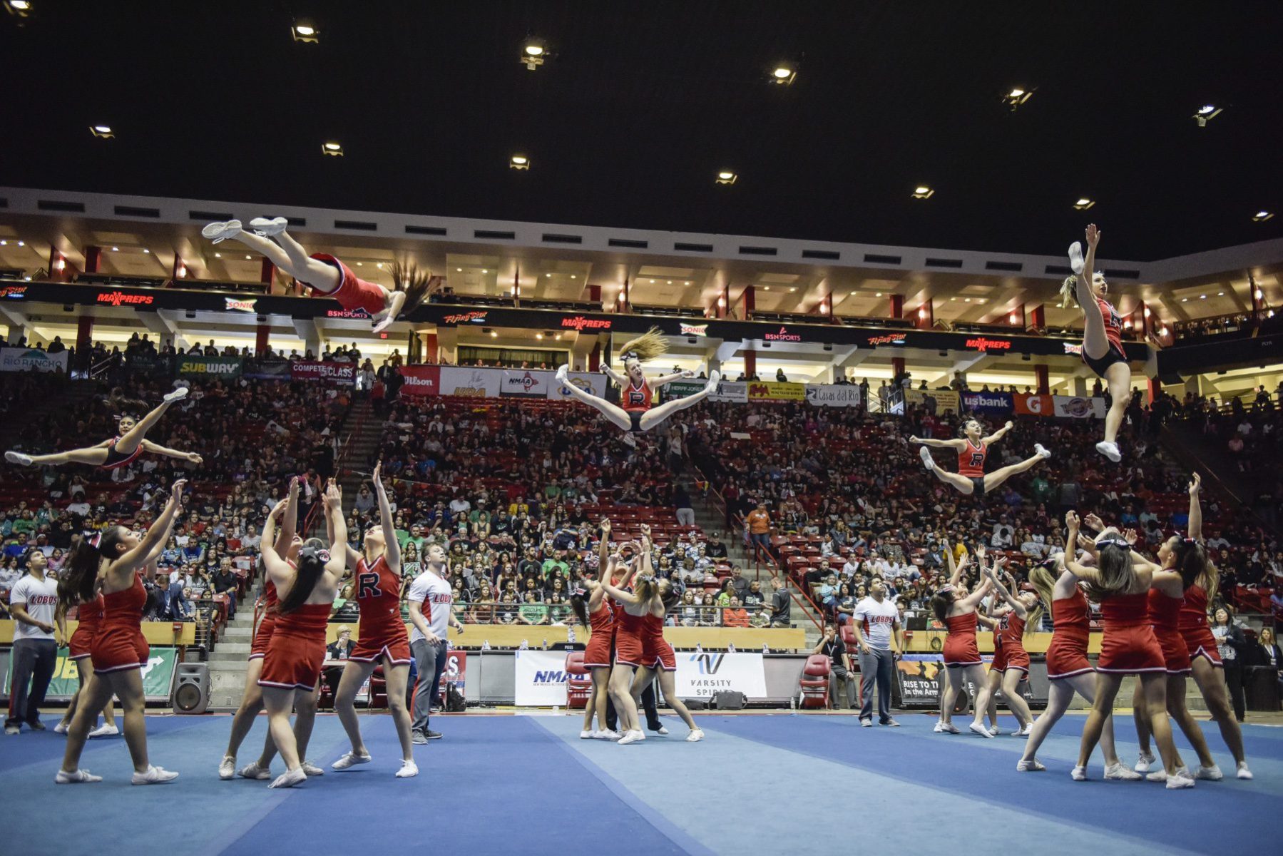 Cheerleaders doing stunts on a competition floor.