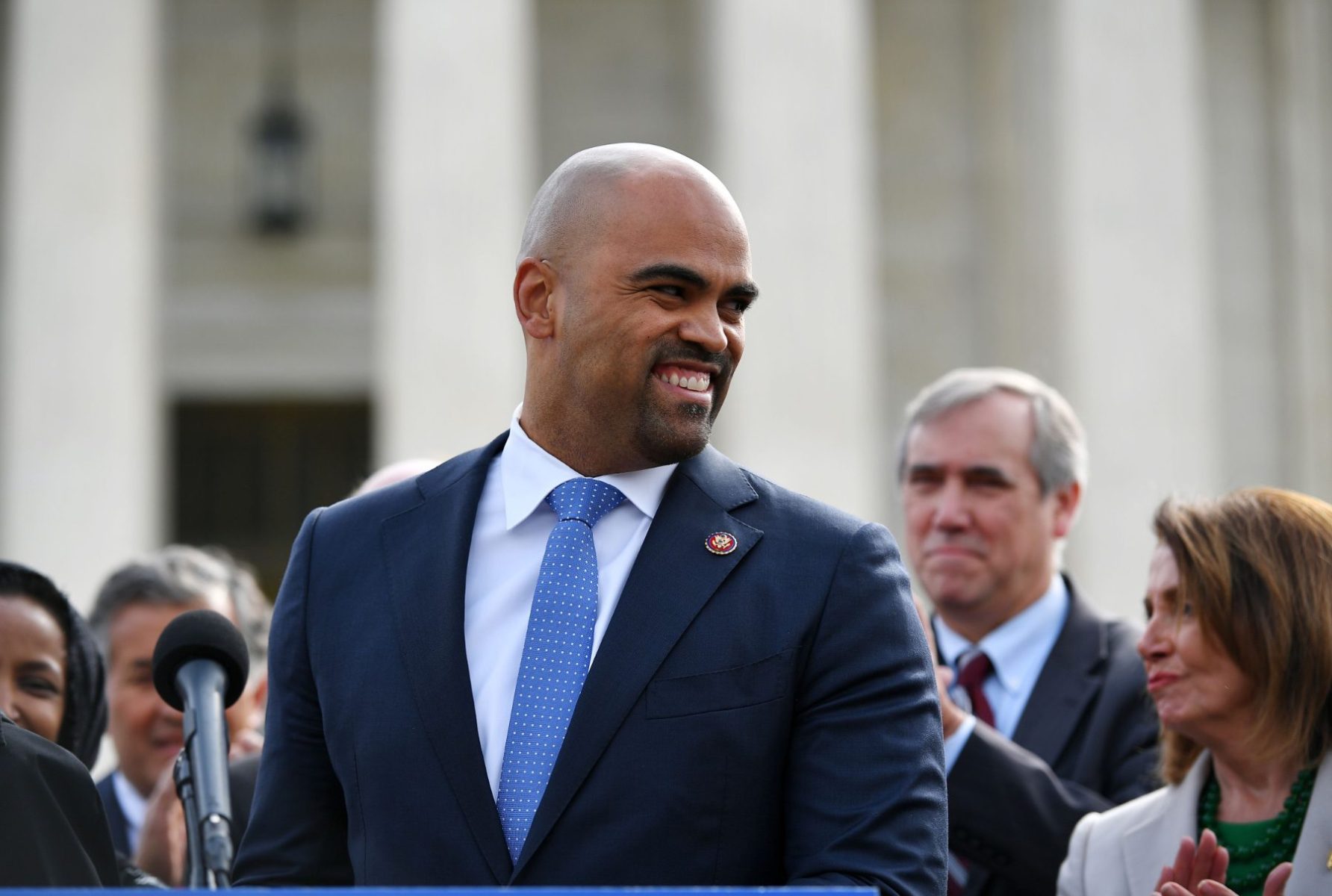 Colin Allred smiling before a microphone.