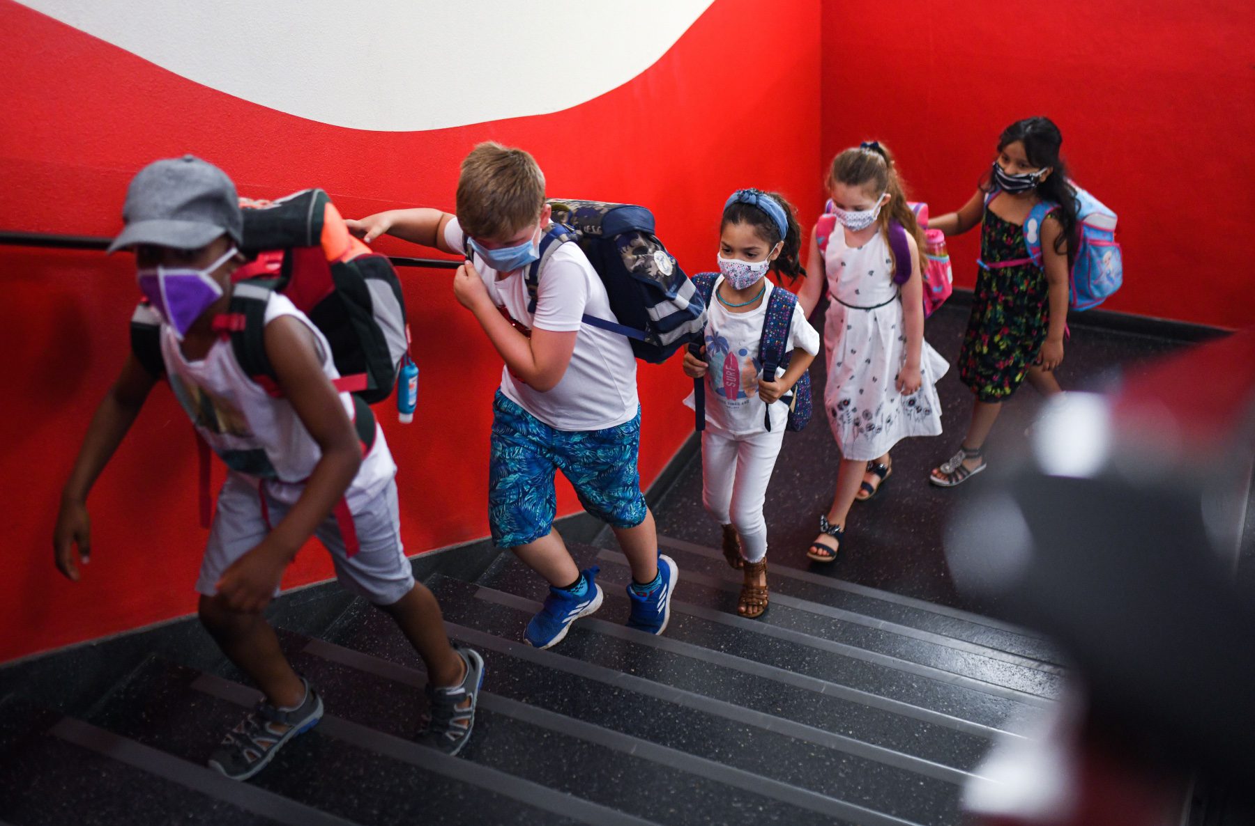 School children wearing masks in a hallway.