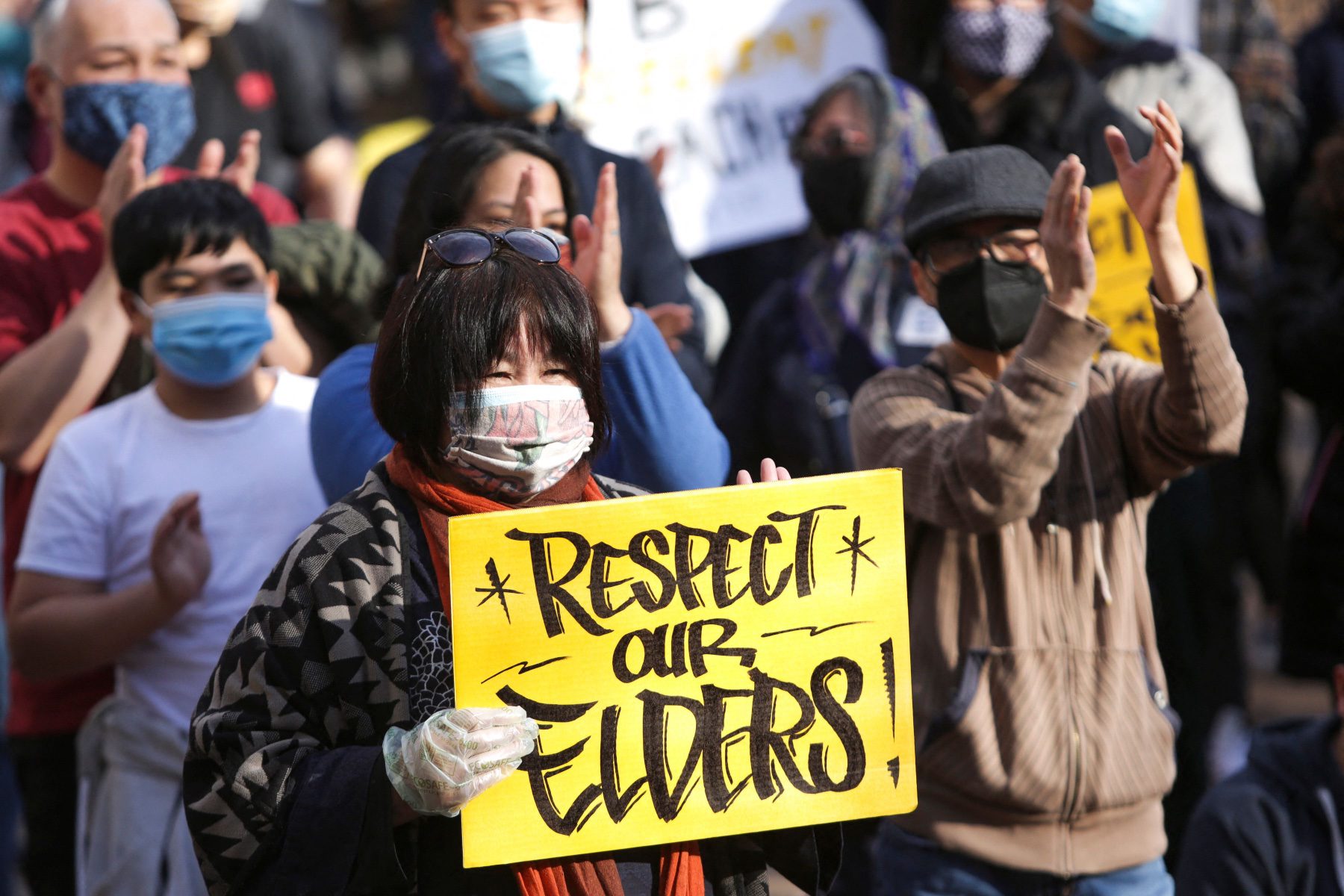 A woman holds a sign that reads "Respect Our Elders."