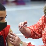 School nurse Kim Davey administers a COVID-19 vaccine.