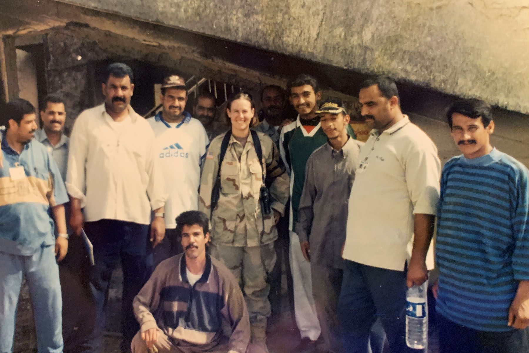 Veteran Bernadette Frudge poses for a picture surrounded by men in civil attire.