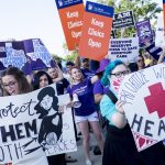 Activists hold signs both for and against abortion.