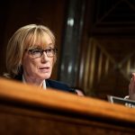 Margaret Hassan is seen at behind a desk while she speaks in Congress.