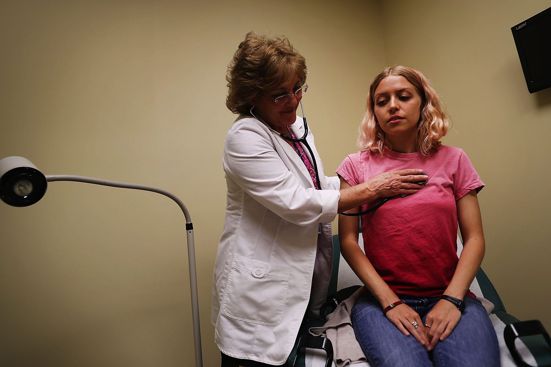 A woman is examined by a nurse in an examination room.