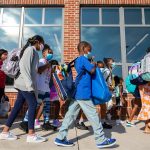 Young students wearing face masks prepare to enter their elementary school on the first day of classes.