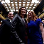 Gretchen Whitmer, Frank Liberati and Mallory McMorrow smile as people applaud.