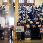 LGBTQ+ rights supporters inside the Texas State Capitol. Many hold signs, some read 