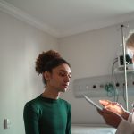 A person speaks with a doctor inside an examination room.