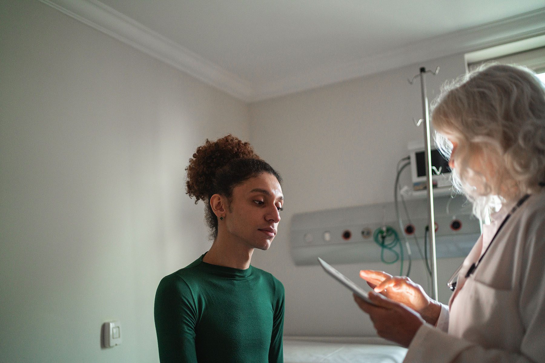 A person speaks with a doctor inside an examination room.