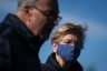 Elizabeth Warren wears a blue face masks and looks on while Chuck Schumer speaks.