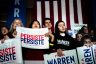 Warren supporters holding signs that say "Persist" look on.