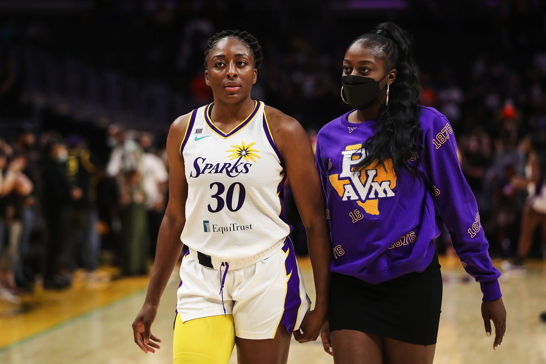 Nneka Ogwumike and Chiney Ogwumike walk together in a basketball stadium.