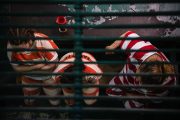 Three female inmates wearing orange and white striped prison uniforms sit on a bench.