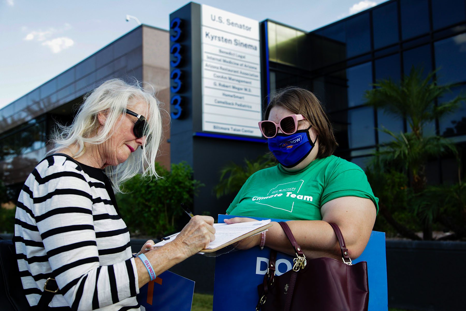 Women attend a rally in front of Kyrsten Sinema's office.