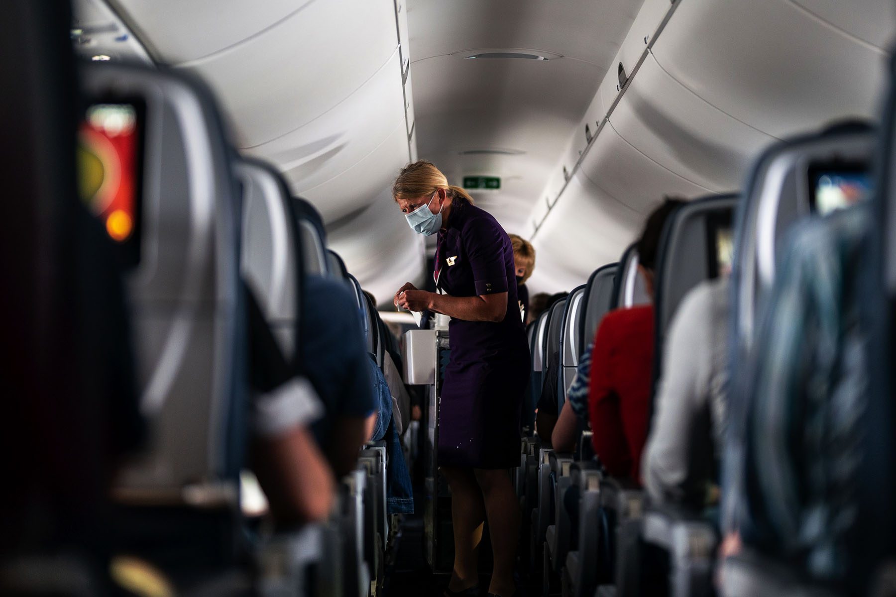 Flight attendants hand out refreshments to a packed Delta Airlines flight.