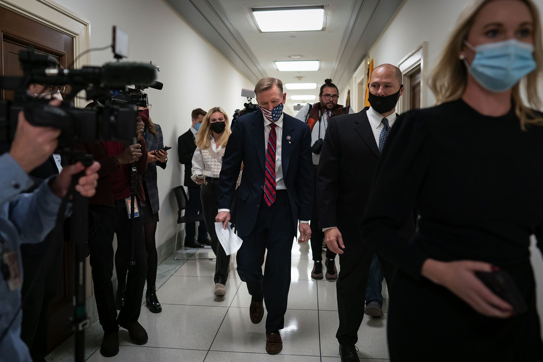 Paul Gosar leaves his office surrounded by press cameras and microphones.