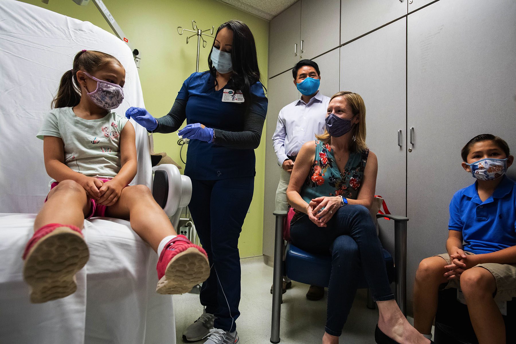 A 6 year old little girl gets a shot of the COVID-19 vaccine while her family watches.