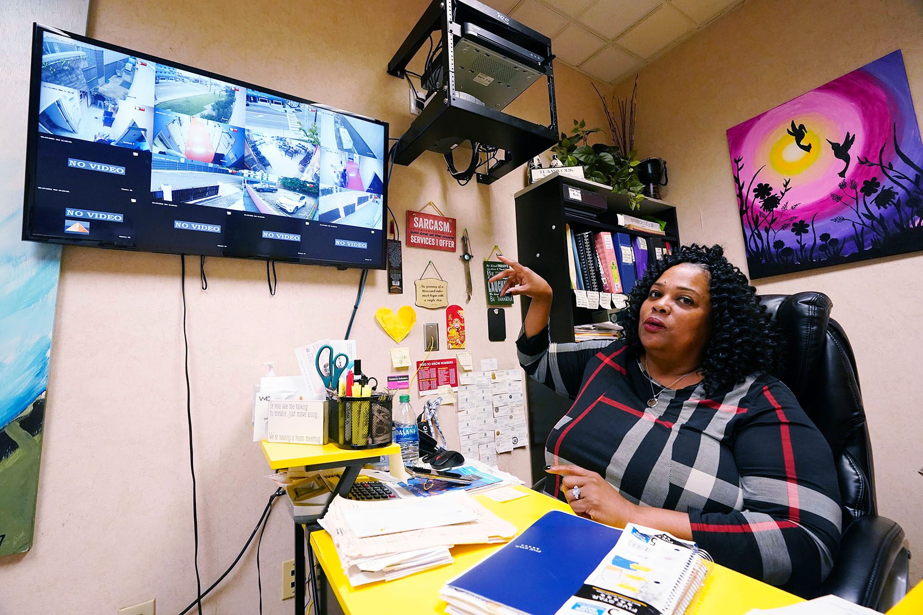 Shannon Brewer points to a TV screen on which an array of security camera feeds are displayed.