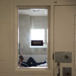 A woman lies down as she reads a book at a prison infirmary.