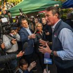 Glenn Younkin speaks to the media at a farmer's market.