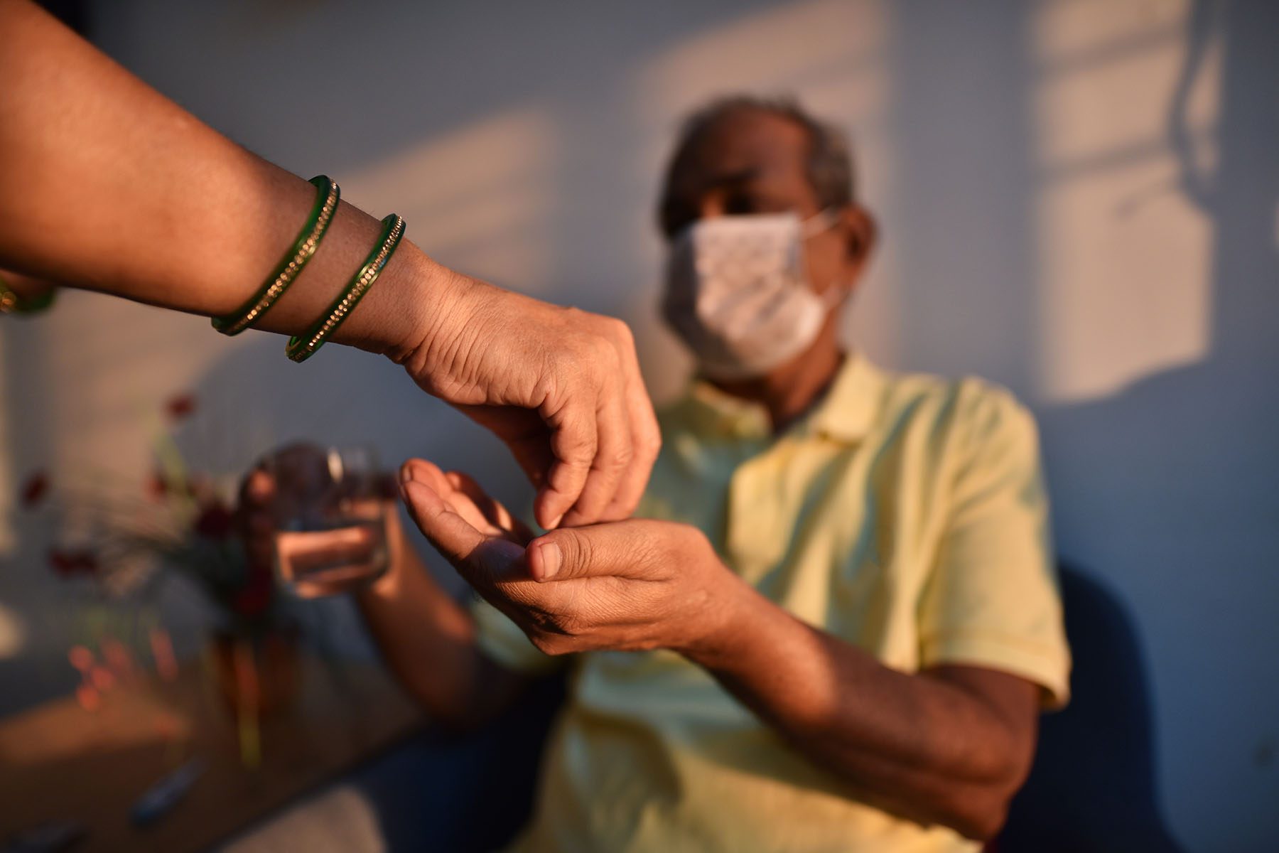 A woman hands a senior man his medicine.