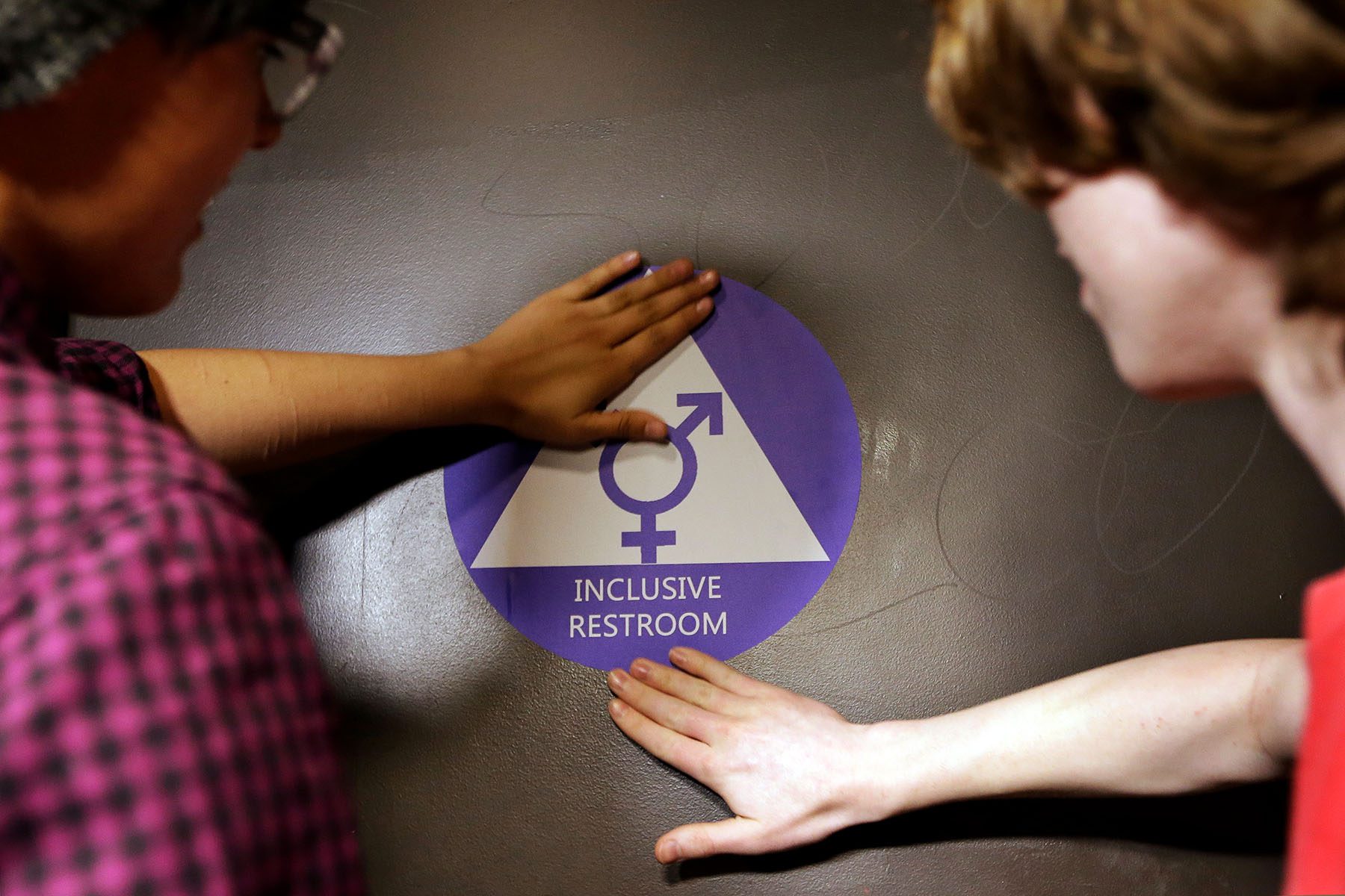 Students place a sticker on the door at the ceremonial opening of a gender neutral bathroom.