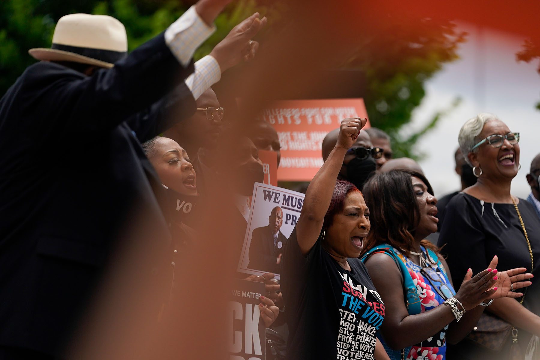 People hold signs and cheer at a voting rights rally.