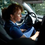 A caregiver looks out her car window contemplatively.