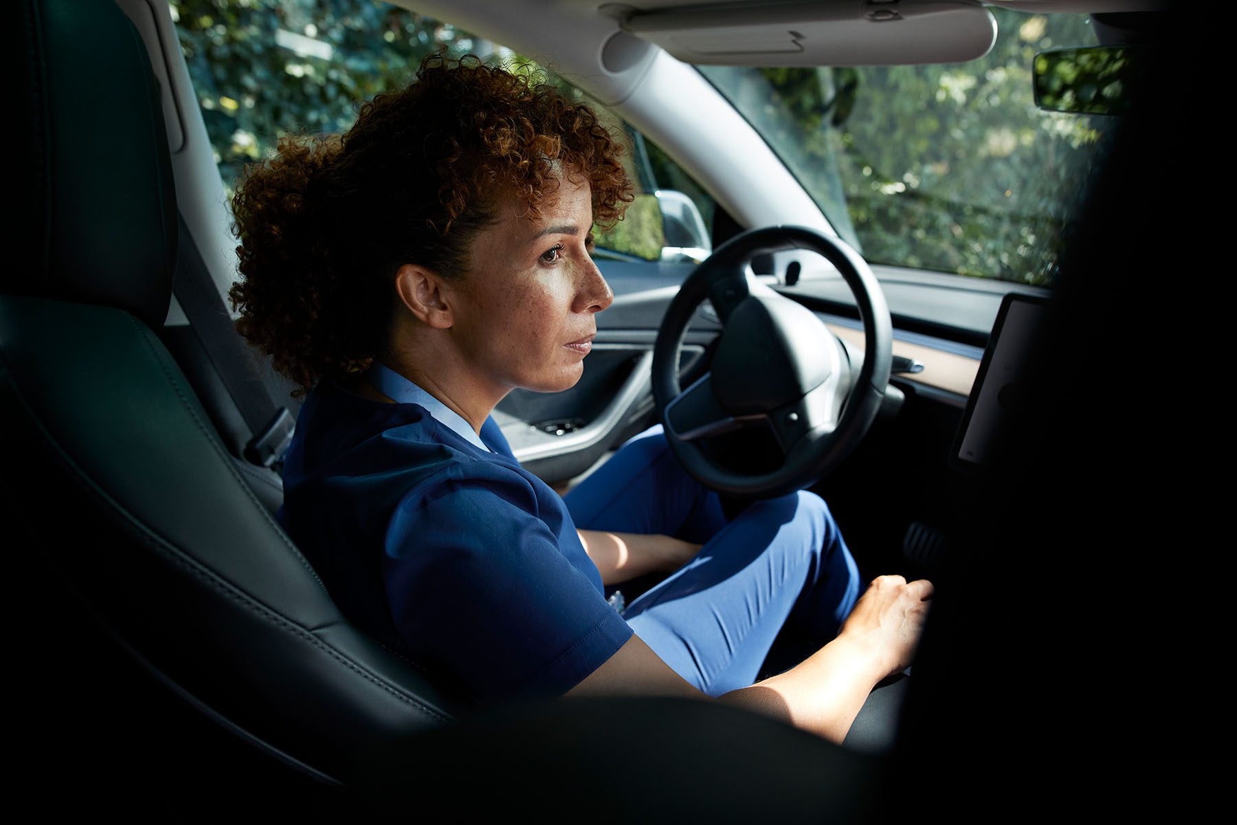 A caregiver looks out her car window contemplatively.