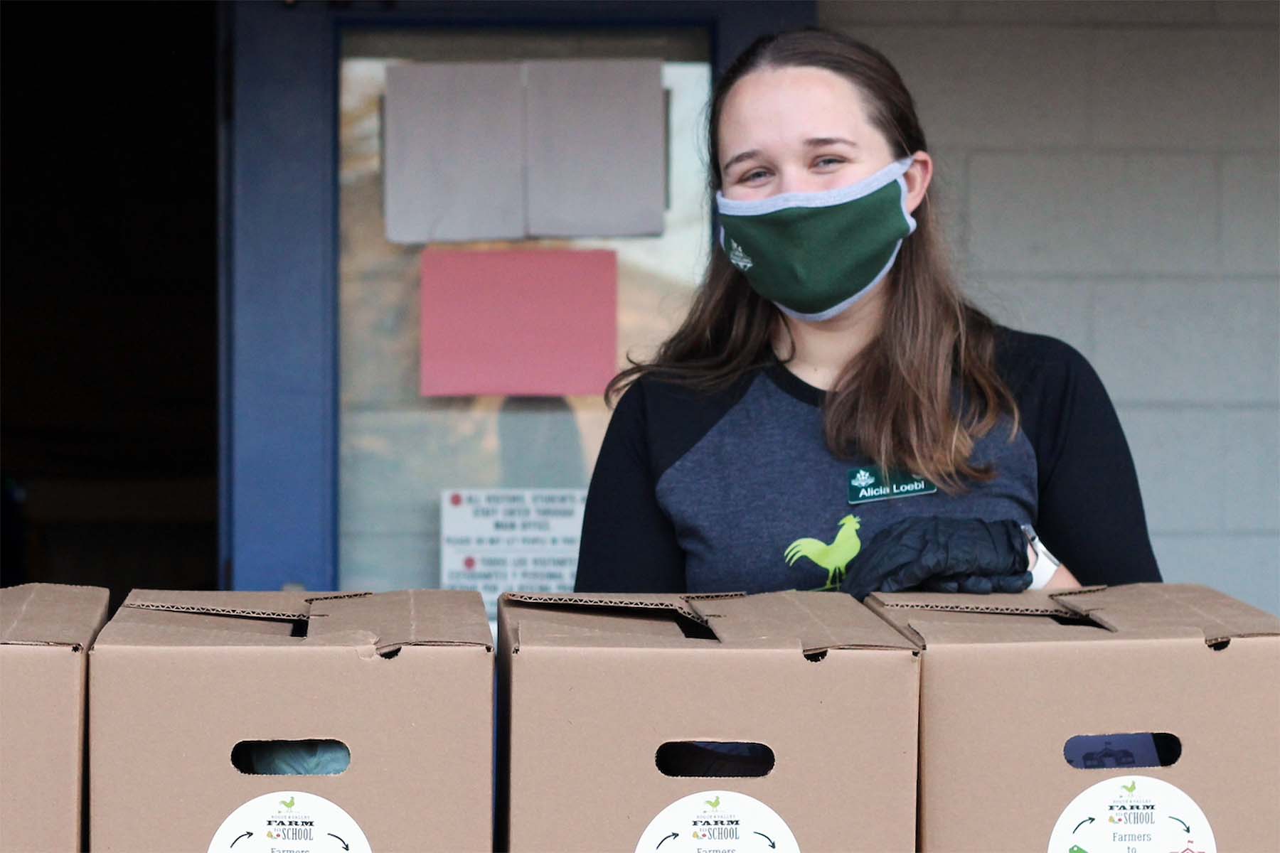 Alicia Loebl poses in front of boxes of free produce.