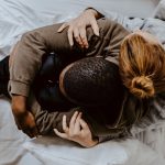 person comforting another person on a bed, as seen from above.