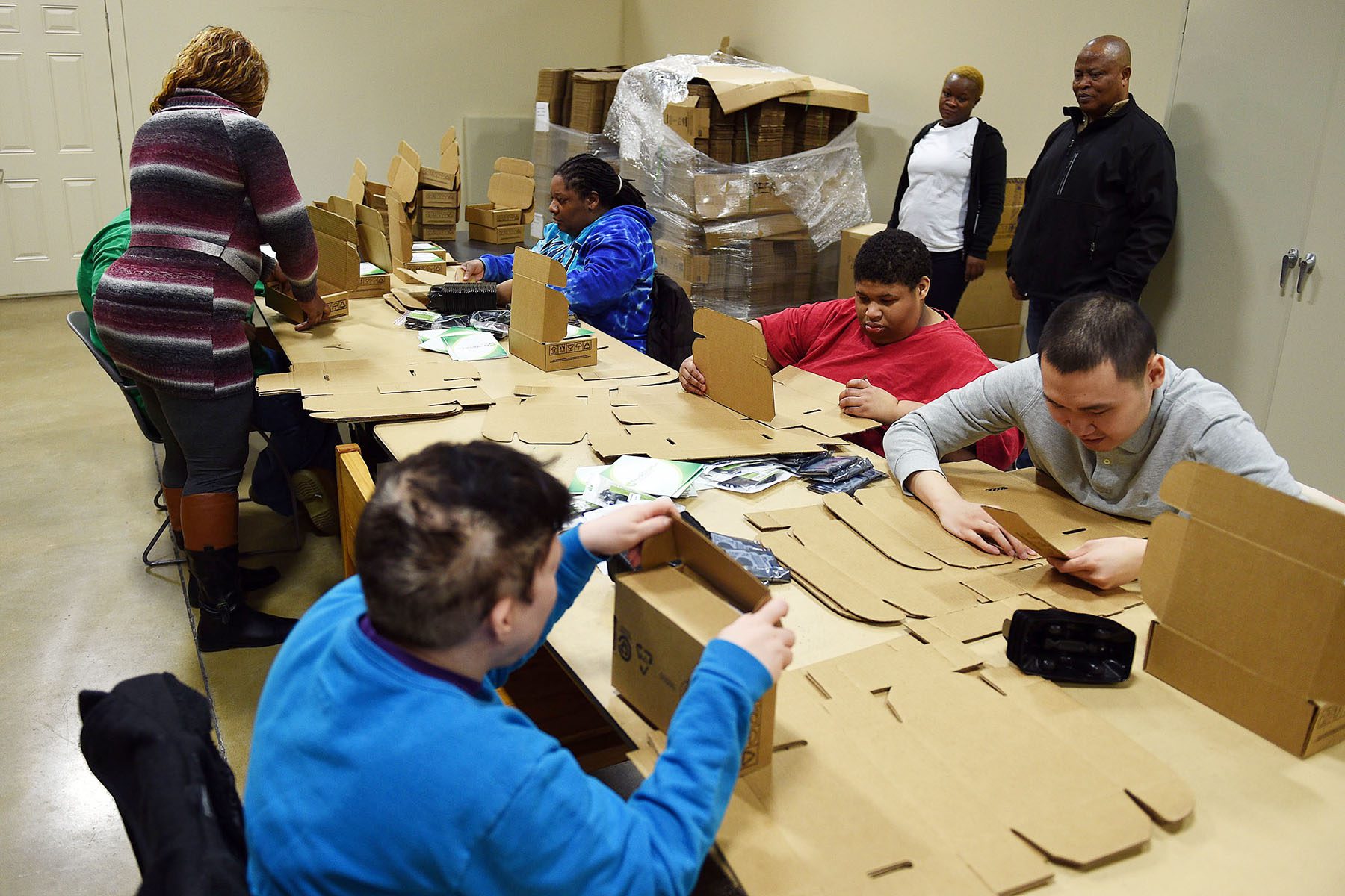 Workers sit around a table while taking care of shipping orders.