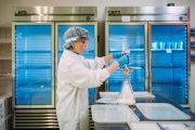 A woman in a lab coat and face shield prepares milk in a laboratory.