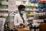 Woman pharmacist with face mask working in a drug store.