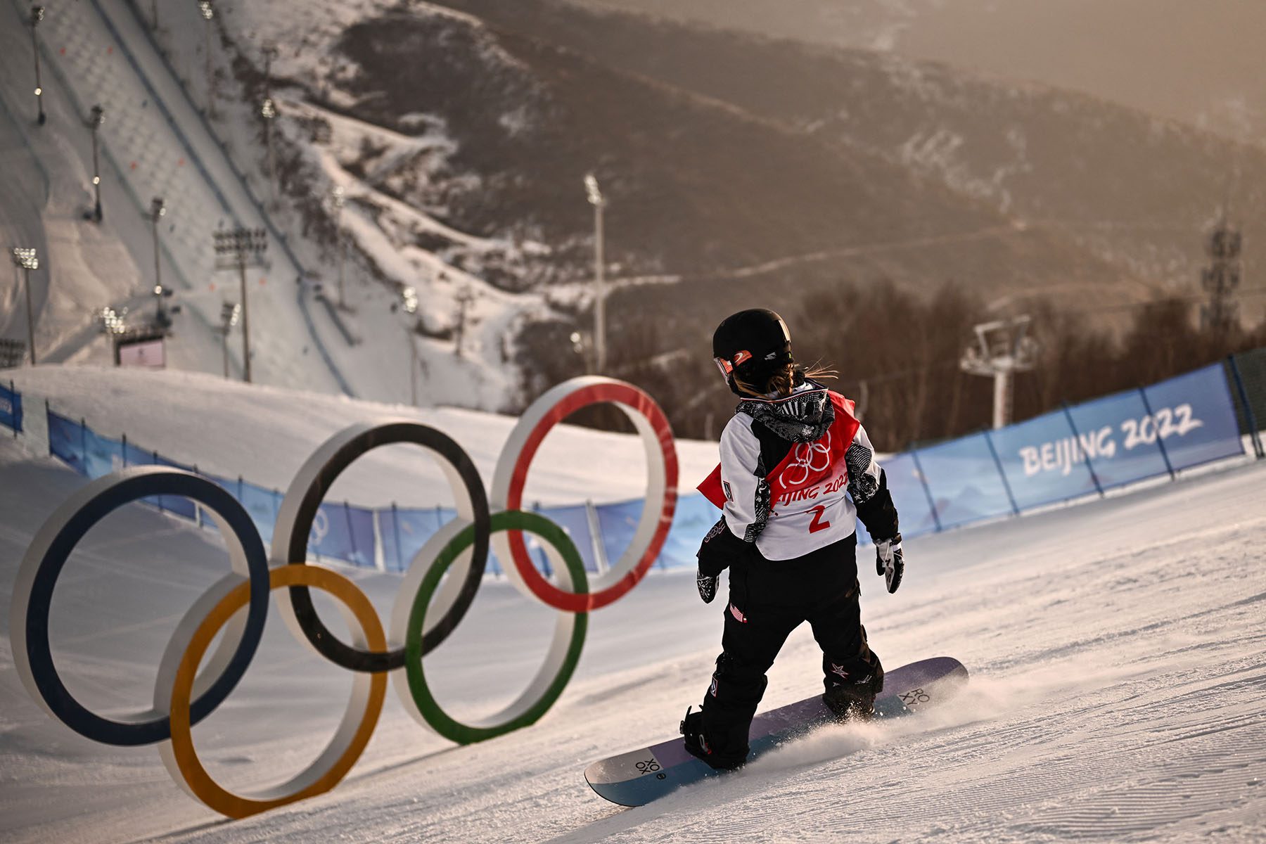 Chloe Kim is seen snowboarding near Olympic rings.