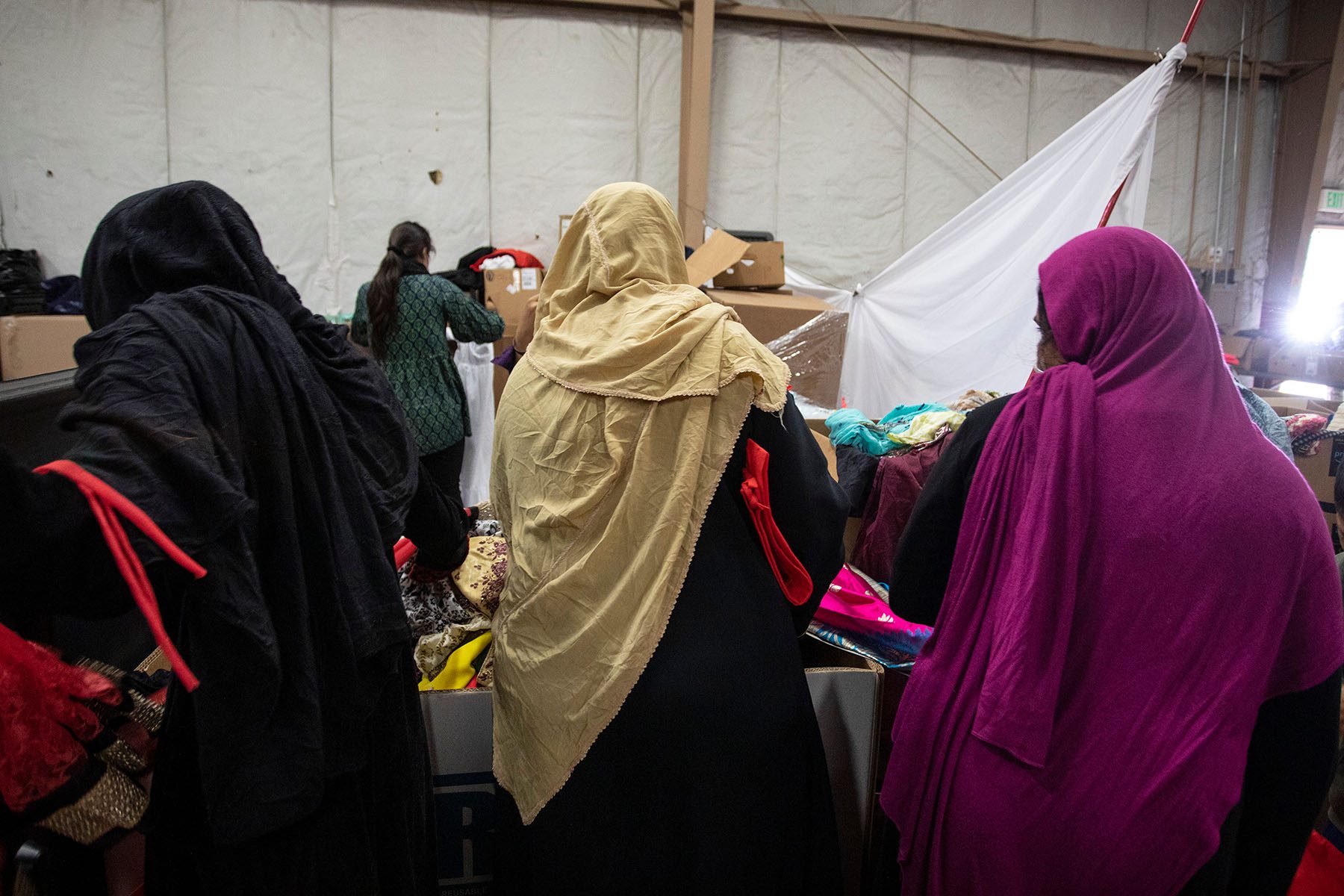 Afghan refugees look through donated clothing and shoes bins.