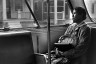 A woman looks out the window as she rides a bus home from work.