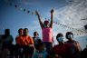 A young girl cheers as other wearing face masks spectators watch a pig race.