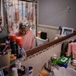 A woman is helped by her caregiver as she brushes her teeth.