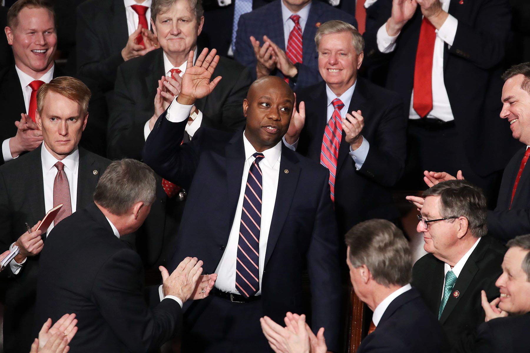 Sen. Tim Scott waves as his colleagues applaud him.