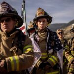 Firefighters in full gear observe a moment of silence.