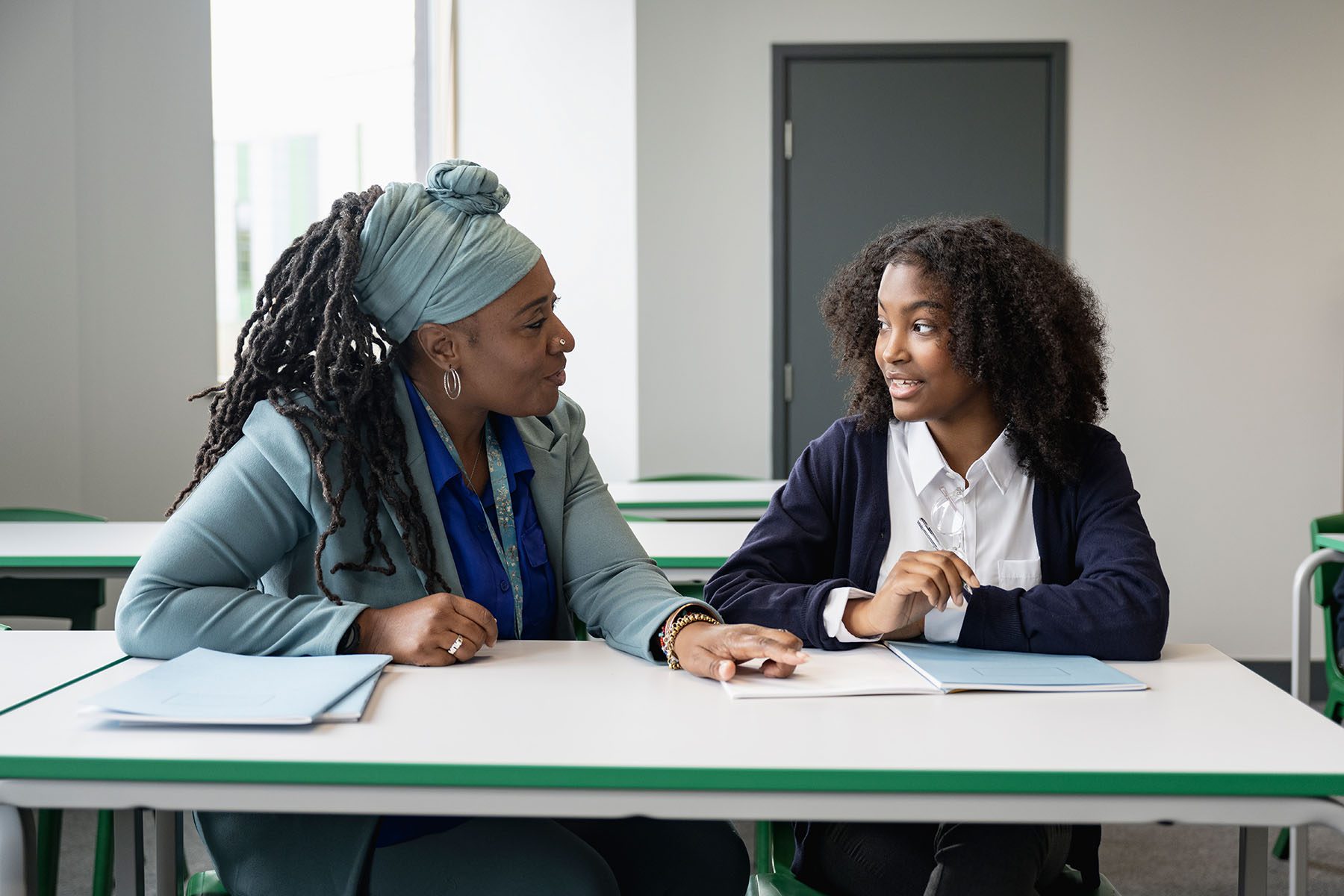 Black educator working with multiracial student in classroom.