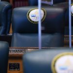 Empty desks and desk chairs are seen at the Colorado State Capitol. The chair are engraved with a 