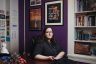 Julia Bascom poses in her DC office. There are pictures on the wall and knickknacks on the desk. Behind her two posters read 