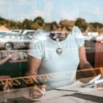 A black woman writes reservations down in a small restaurant.