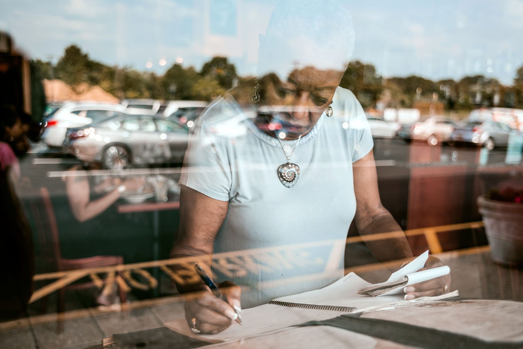 A black woman writes reservations down in a small restaurant.