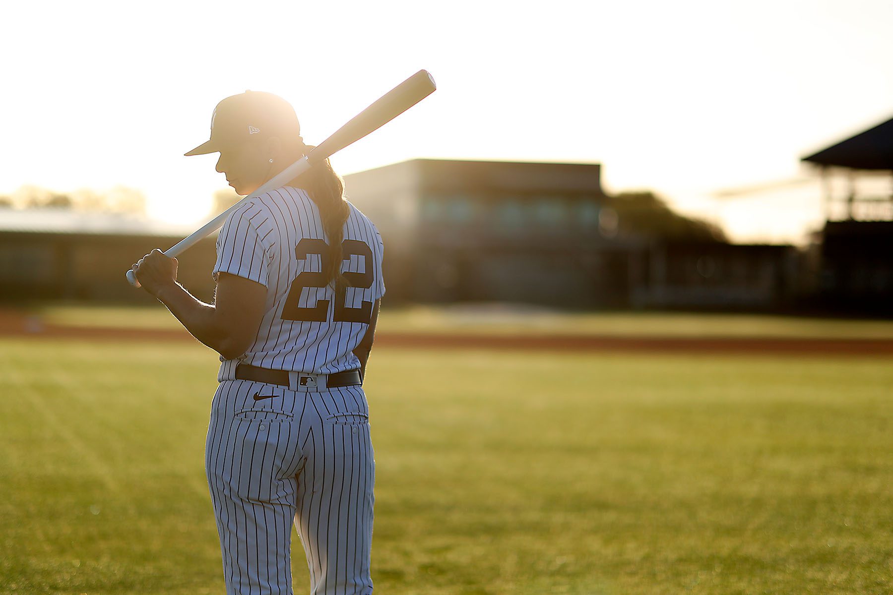 Rachel Balkovec in seen in full uniform holding a baseball bat on a baseball field.