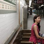 An asian woman in a pink dress waits for the subway in New York City.